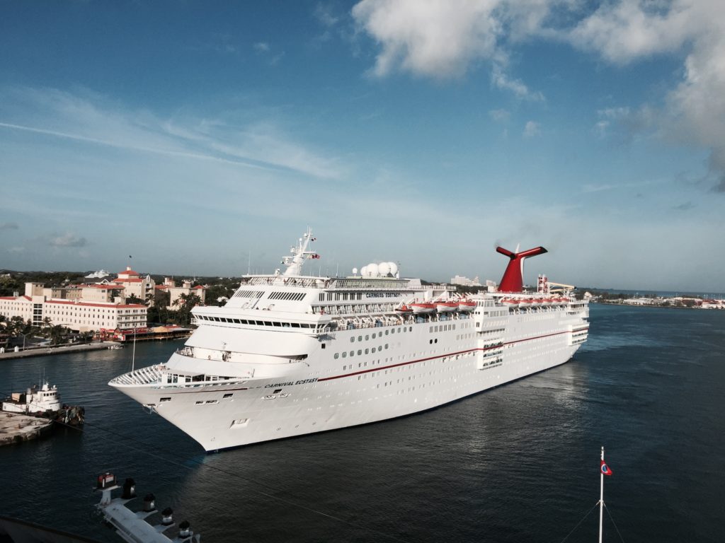 Cruise ship Carnival Ecstasy entering Nassau in the Bahamas in 2015. Viewed from the deck of the Carnival Fantasy, which docked a few minutes before. Wikimedia Commons: Arnold Reinhold license: https://bit.ly/3p0X5dt